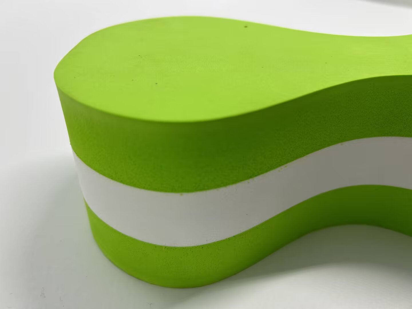 Green and white layered foam shape with smooth curved edges from oscillating knife cutting
