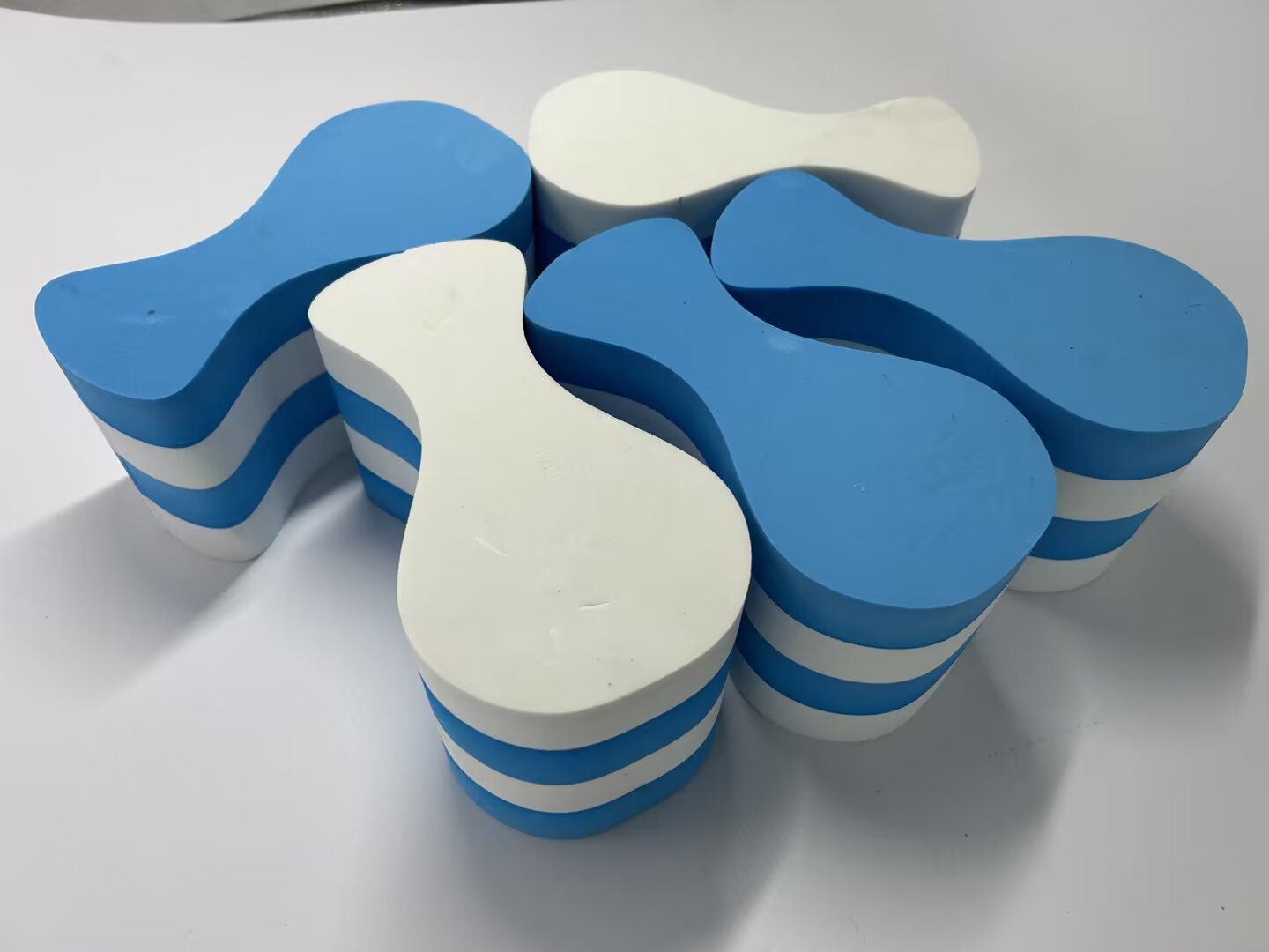 Blue and white layered EVA foam shapes cut with clean edges by oscillating knife